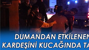 Dumandan etkilenen kardeşini kucağında taşıdı
